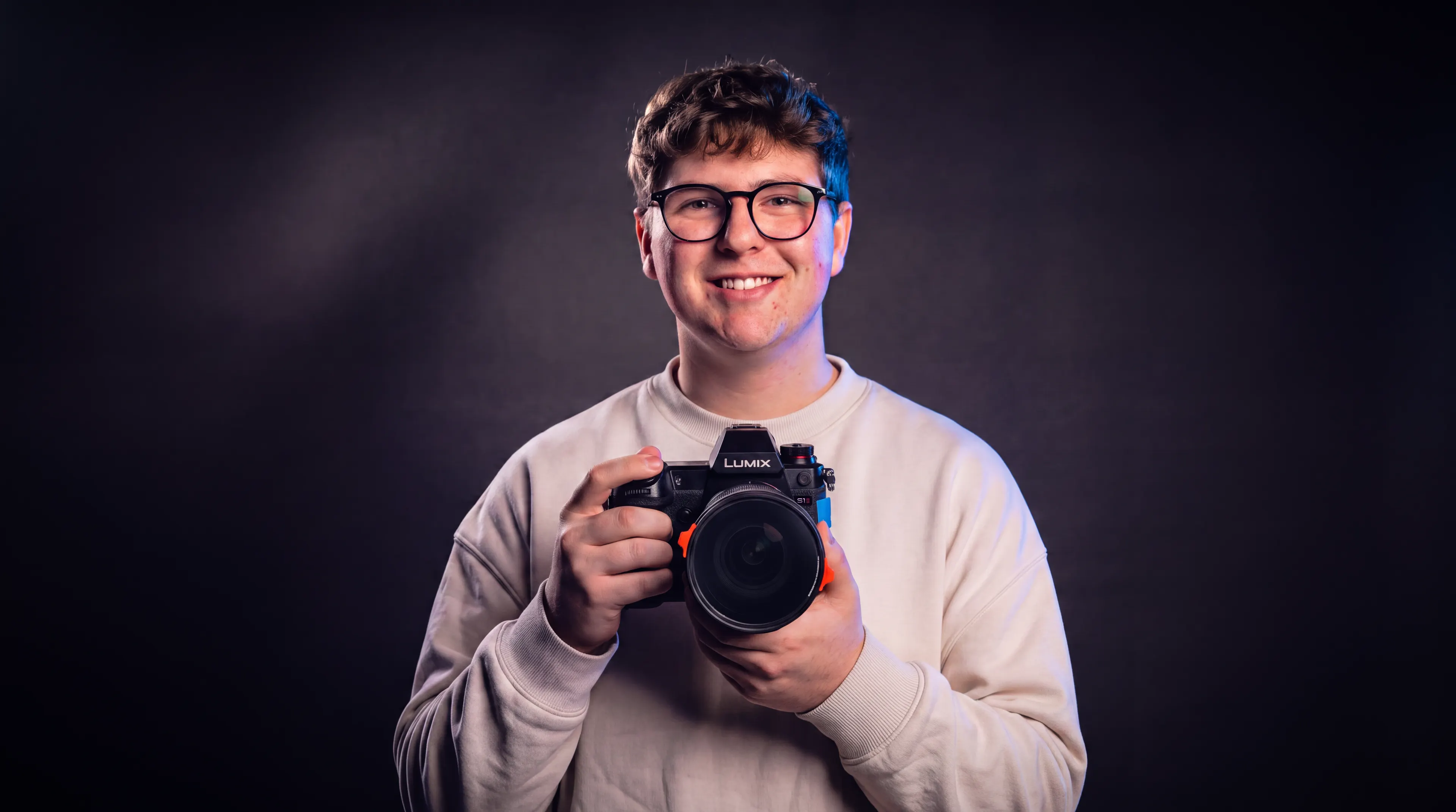 Marc sonriendo con su cámara Lumix en las manos, la lente mirando a cámara